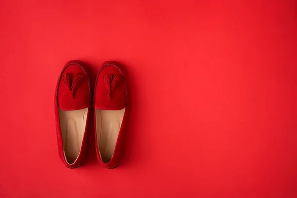 赤い背景の上に赤いスエードの女性のモカシンの靴 — ストック写真