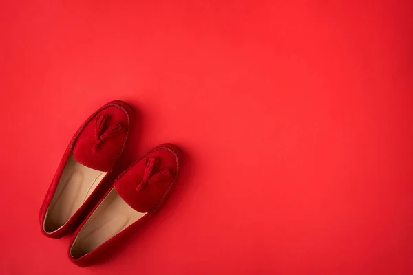 Red suede woman's mocassin shoes over red background — Stock Photo, Image