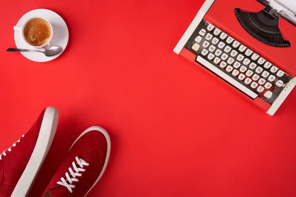 Klarröda skor, skrivmaskin och kaffekopp på röd bakgrund — Stockfoto