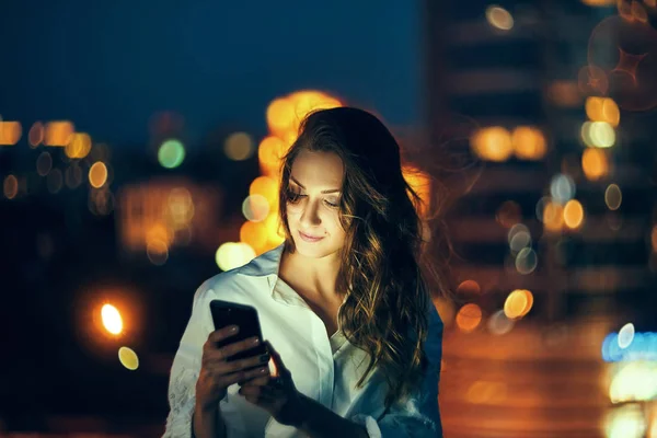 スマートフォンのテキストメッセージを保持している都市景観上の女性 — ストック写真