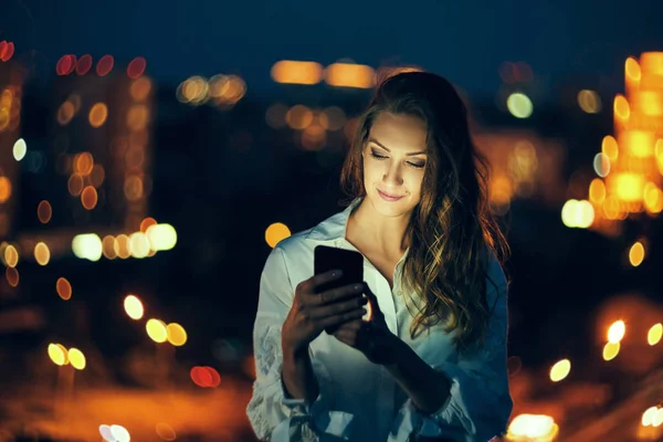 Женщина над городским пейзажем держит смс-ку со смартфона — стоковое фото