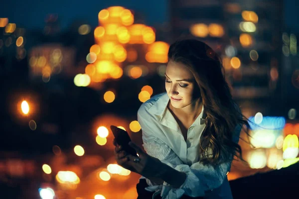 Mujer sobre paisaje urbano sosteniendo un teléfono inteligente mensajes de texto — Foto de Stock