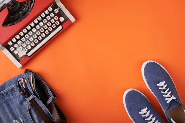 Blå mocka sneakers skor, nödställda jeans och skrivmaskin på Orange bakgrund — Stockfoto