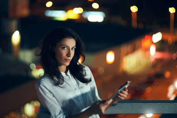 Mujer durante la noche paisaje urbano sosteniendo una tableta digital mensajes de texto — Foto de Stock