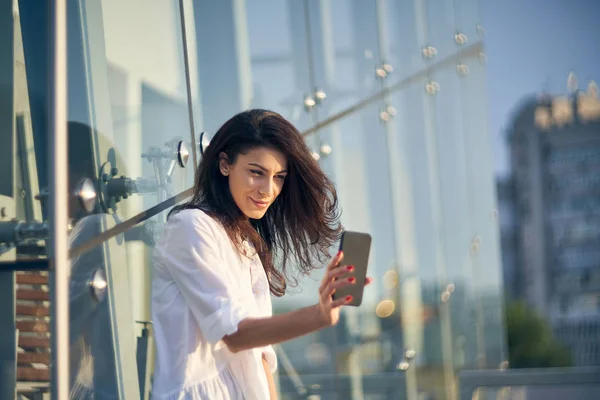 Mujer haciendo autorretrato con su teléfono inteligente sobre el edificio de oficinas moderno —  Fotos de Stock