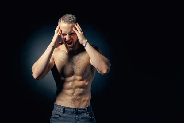 Muscular shirtless man screaming holding head in hands — Stock Photo, Image