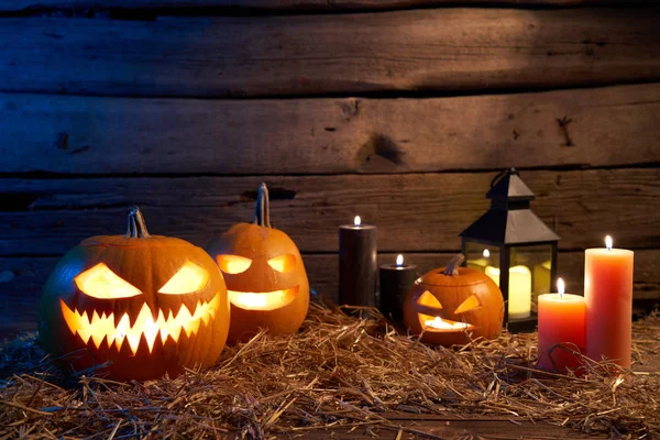 Jack-O-Lantern Halloween pumpkins on rough wooden planks with candles — Stock Photo, Image