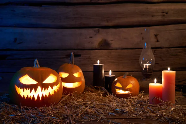 Jack-O-Lantern Halloween pumpkins on rough wooden planks with candles — Stock Photo, Image