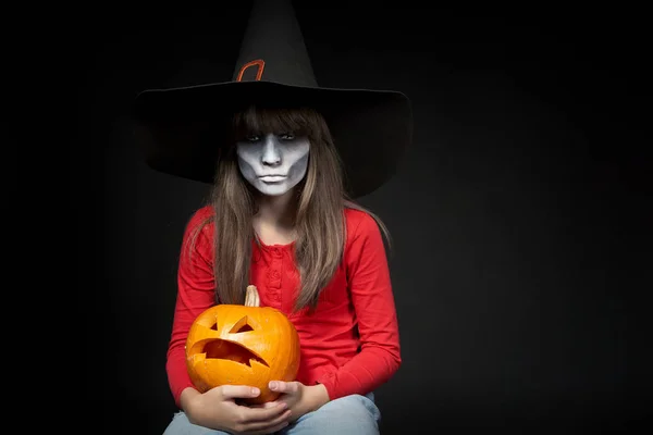 Súlyos Halloween boszorkány gazdaság Jack Olantern sütőtök nézi kamera — Stock Fotó