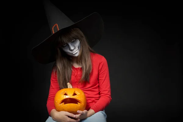 Súlyos Halloween boszorkány gazdaság Jack Olantern sütőtök nézi kamera — Stock Fotó