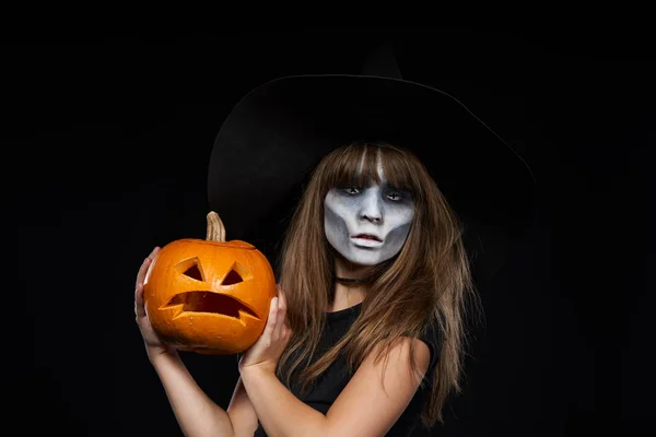 Allvarliga Halloween häxa Holding Jack-O-Lantern pumpa tittar på kamera — Stockfoto