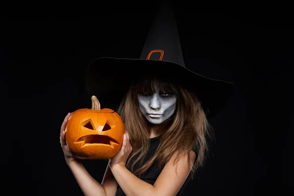Súlyos Halloween boszorkány gazdaság Jack-O-Lantern sütőtök nézi kamera — Stock Fotó