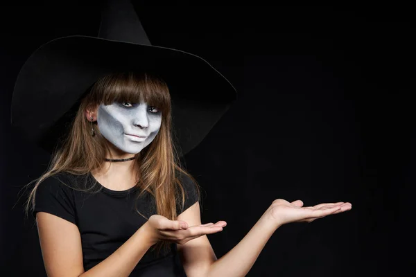 Halloween bruxa olhando para a câmera mostrando espaço em branco cópia em suas palmas — Fotografia de Stock