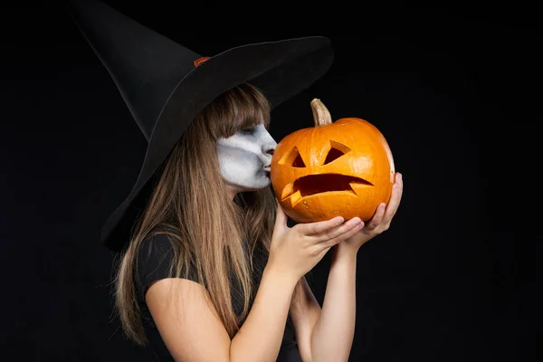 Halloween häxa flicka som ger en kyss till Jack-O-Lantern Pumpkin — Stockfoto