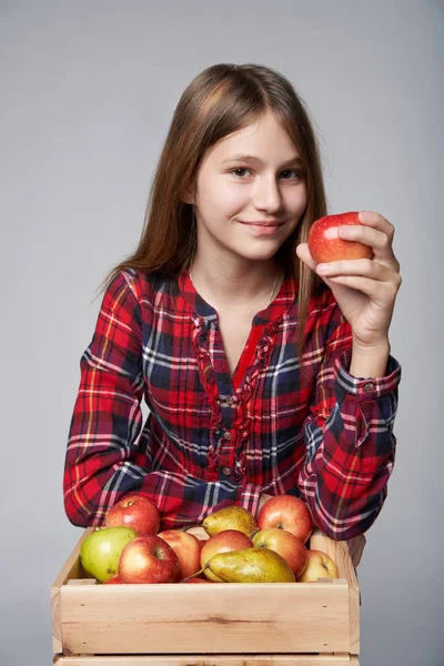 Девочка-подросток с яблоками и грушами в коробке — стоковое фото