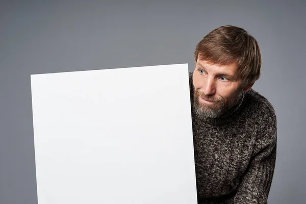 Sorridente uomo maturo in maglione caldo con banner bianco che lo guarda — Foto Stock