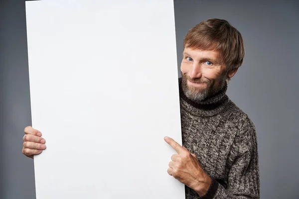 Sorridente uomo maturo in maglione caldo tenendo banner bianco — Foto Stock