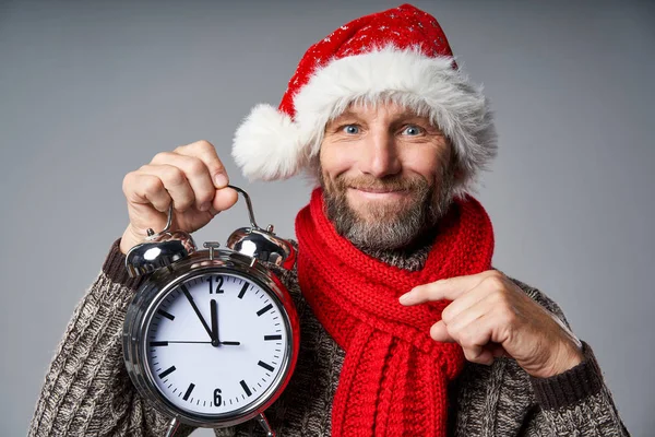 Sonriente hombre maduro con sombrero de Santa celebración de reloj despertador grande —  Fotos de Stock