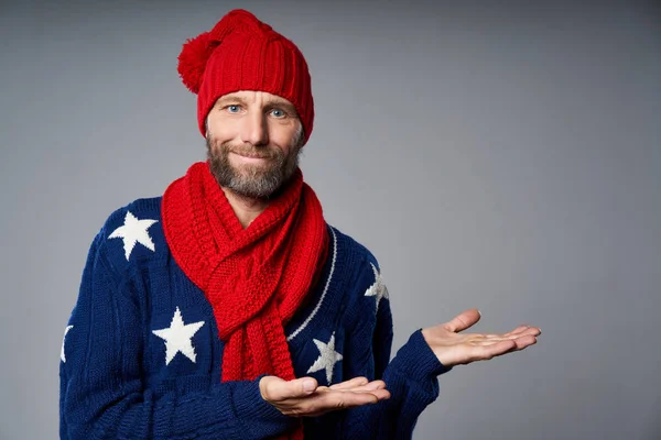 Usmívající se dospělý muž v jasně červené pletený klobouk a šála gestikulující palec nahoru — Stock fotografie