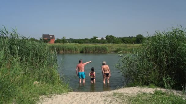 Familia con hija de pie en aguas poco profundas del río y hablando — Vídeos de Stock