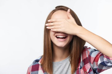 Emotional happy teen girl covering her eyes with palm laughing clipart