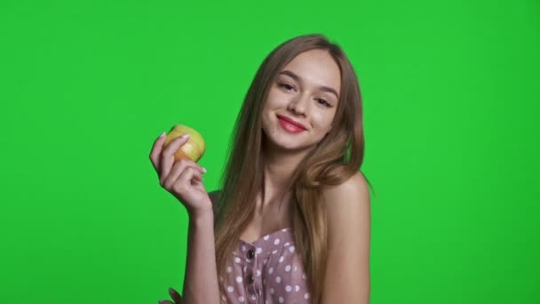 Uśmiechnięta dziewczyna w letniej sukience uśmiechnięta i trzymająca zielone jabłko — Wideo stockowe