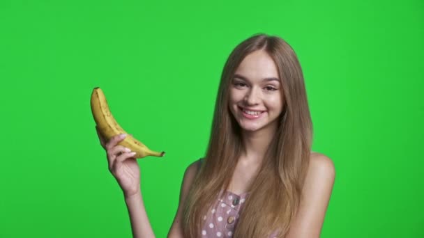 Uśmiechnięta Dziewczyna Letniej Sukience Uśmiechnięta Pokazująca Banana Odizolowana Zielonym Tle — Wideo stockowe