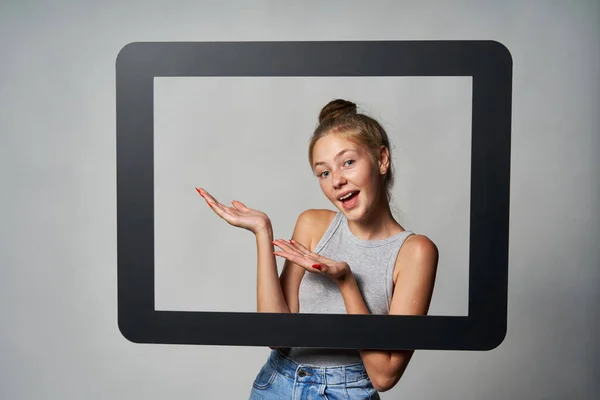 Gadis remaja yang gembira melihat melalui bingkai tablet digital dan menampilkan ruang salinan kosong — Stok Foto