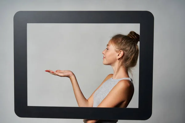 Profil gadis yang berdiri di belakang bingkai tablet digital dan menampilkan ruang salinan kosong di telapak tangannya — Stok Foto