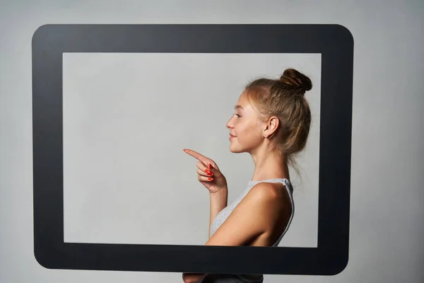 Perfil da menina de pé atrás do quadro tablet digital e apontando um dedo para espaço de cópia em branco — Fotografia de Stock