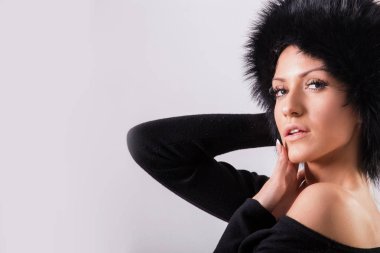 Siyah giysiler ve beyaz arka plan üzerinde siyah kürk şapka duran güzellik kadın portresi stüdyo