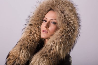 Siyah giysiler ve siyah deri ceket kürk yaka, beyaz duvar arka plan ile duran güzellik kadın portresi stüdyo