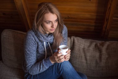 Beyaz Kupası ahşap evde kanepede oturan güzel kadınla