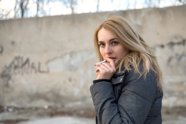 Sokakta sigara ve kameraya bakıyor güzel kadın