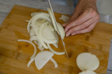 kadın aşçı bıçak ve kesici soğan, mutfak, ahşap kesme tahtası üzerinde tutarak yakın çekim 