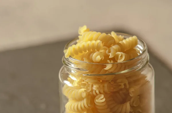 unprocessed pasta in glass jar on tabletop in kitchen