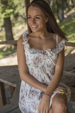 gülümseyen genç kadın oyuk niteliğine tablosunda oturan ve uzak arıyorum yaz elbise