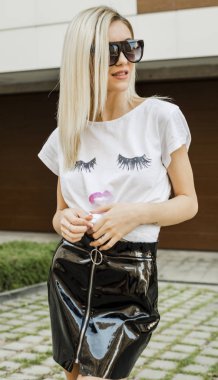 gülümseyen genç kadın beyaz t-shirt ve sokakta duran etek