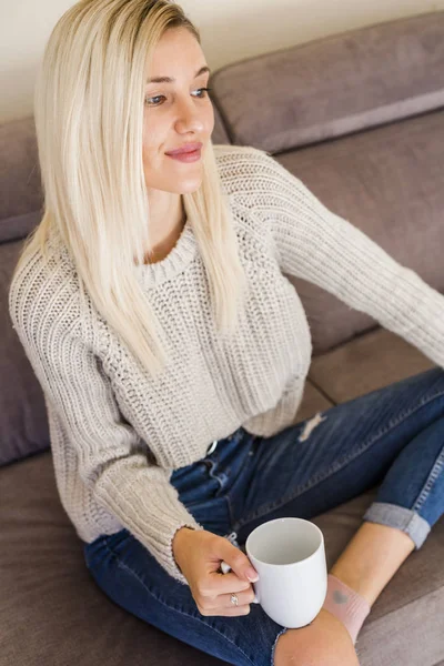 한잔과 소파에 청바지와 스웨터 편안한 여자의 — 스톡 사진