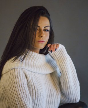 Portre studio gri arka plan üzerinde beyaz kazak giyen güzellik esmer kadın portresi