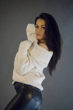 Portre studio gri arka plan üzerinde beyaz kazak giyen güzellik esmer kadın portresi