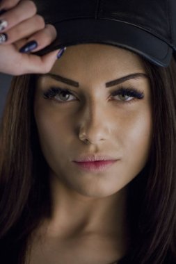 Siyah giysiler ve mavi arka plan üzerinde siyah kap duran güzellik esmer kadın portre studio portresi