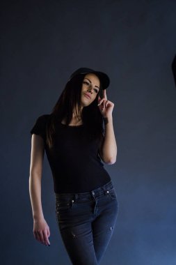 Siyah giysiler ve mavi arka plan üzerinde siyah kap duran güzellik esmer kadın portre studio portresi