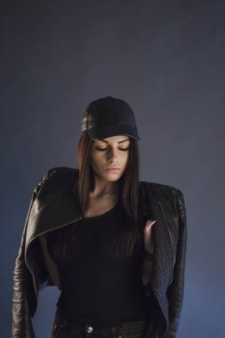 şık esmer kadın deri kap giyen ve kamera poz stüdyo çekim, aşağı bakıyor 