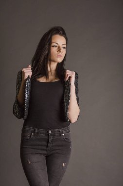 Stüdyoda poz veren parlak leopar ceketli esmer kadın.