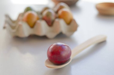 Arka planda yumurta kutusu ile tahta kaşıkta boyalı kırmızı yumurta yakın görünümü
