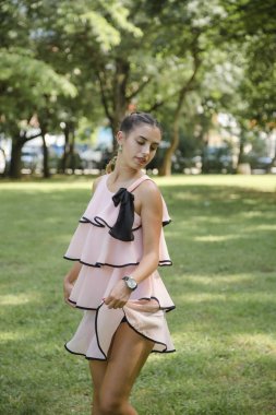 yazlık parkta pembe elbise poz makyaj ve saç modeli ile çekici genç esmer kadın