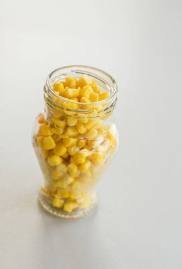 açık arka plan üzerinde cam kavanozda sarı mısır taneleri yığını, yakın çekim 