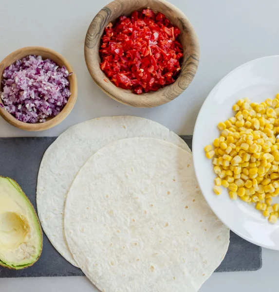 ingredients for Mexican vegetarian tacos in bowls on light table, close-up