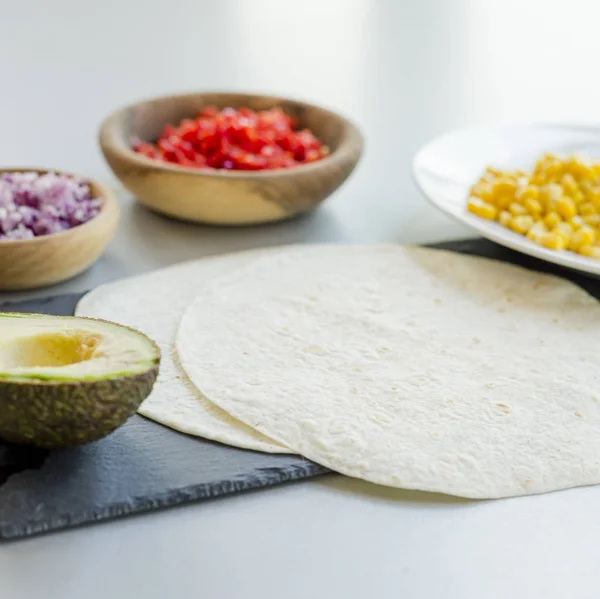 ingredients for Mexican vegetarian tacos in bowls on light table, close-up